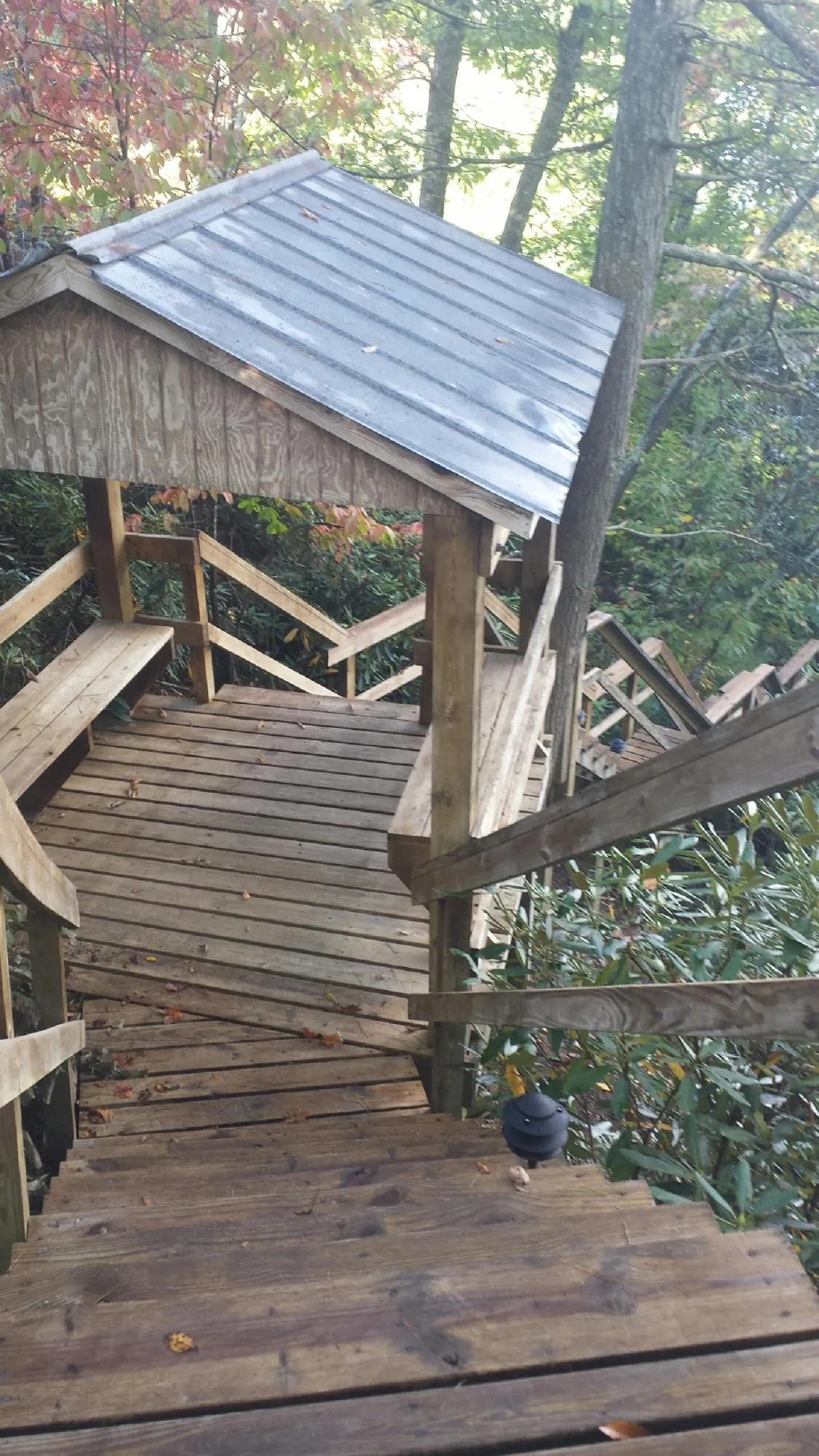 Metal roofed shelter over wooden steps on a wooded walkway — Skylight Repair & Installation work by our crew in East Hampton