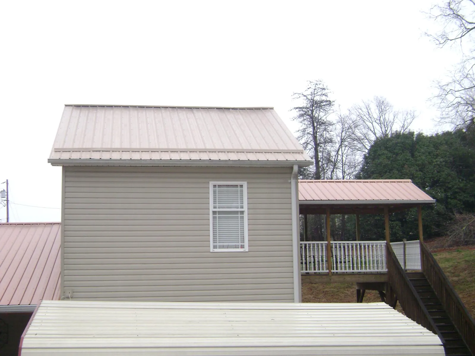 Tan metal roofs on a two story addition and attached porch, from a Roof Replacement job in East Hampton